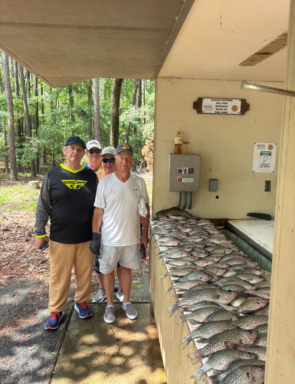 Four anglers standing behind a table filled with their catch